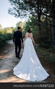 Just married couple walking by the woods with their back to the camera