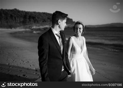 Just married couple walking on a beach on black and white