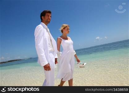 Just married couple walking on a sandy beach