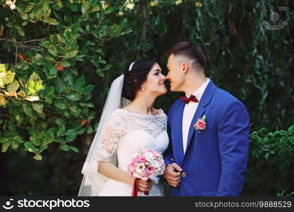 Just married loving hipster couple in wedding dress and suit in the park. Happy bride and groom walking in the beautiful garden. Romantic Married young family. Summer wedding