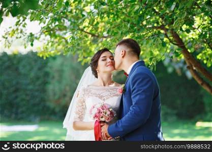 Just married loving hipster couple in wedding dress and suit in the park. Happy bride and groom walking in the beautiful garden. Romantic Married young family. Summer wedding