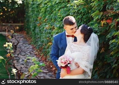 Just married loving hipster couple in wedding dress and suit in the park. Happy bride and groom walking in the beautiful garden. Romantic Married young family. Summer wedding