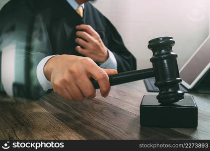 justice and law concept.Male judge in a courtroom striking the gavel,working with digital tablet computer docking keyboard on wood table,filter effect