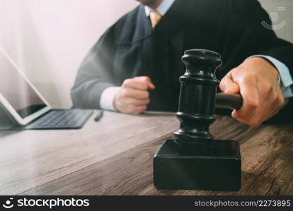 justice and law concept.Male judge in a courtroom striking the gavel,working with digital tablet computer docking keyboard on wood table,filter effect