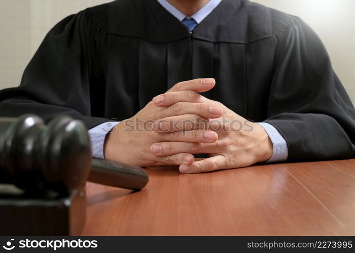 justice and law concept.Male judge in a courtroom striking the gavel,working with digital tablet computer docking keyboard on wood table