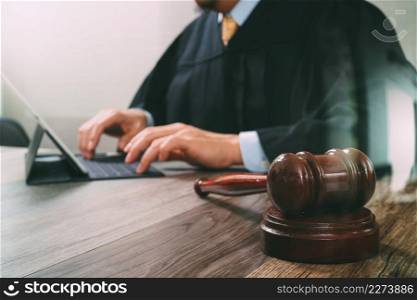 justice and law concept.Male judge in a courtroom with the gavel,working with digital tablet computer docking keyboard on wood table,filter effect