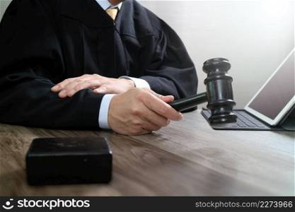 justice and law concept.Male judge in a courtroom with the gavel,working with digital tablet computer docking keyboard on wood table