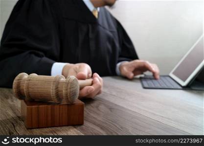 justice and law concept.Male judge in a courtroom with the gavel,working with digital tablet computer docking keyboard on wood table