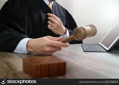 justice and law concept.Male judge in a courtroom with the gavel,working with digital tablet computer docking keyboard on wood table