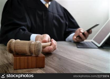 justice and law concept.Male judge in a courtroom with the gavel,working with smart phone,digital tablet computer docking keyboard on wood table