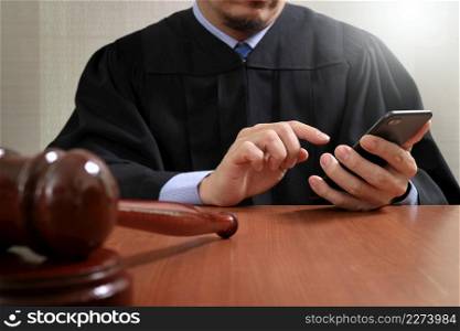 justice and law concept.Male judge in a courtroom with the gavel,working with smart phone computer on wood table