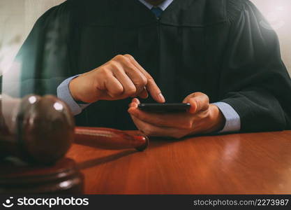 justice and law concept.Male judge in a courtroom with the gavel,working with smart phone computer on wood table,filter effect