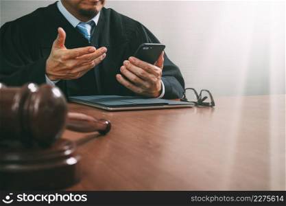 justice and law concept.Male judge in a courtroom with the gavel,working with smart phone,digital tablet computer docking keyboard on wood table,filter effect
