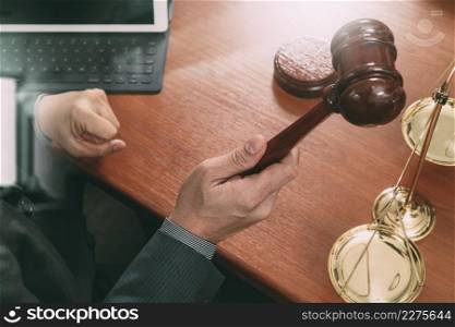justice and law concept.Male judge in a courtroom with the gavel,working with smart phone,digital tablet computer docking keyboard,brass scale,on wood table,filter effect