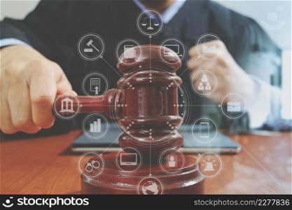 justice and law concept.Male judge in a courtroom with the gavel,working with smart phone,digital tablet computer docking keyboard,eyeglasses,on wood table,virtual interface graphic icons diagram