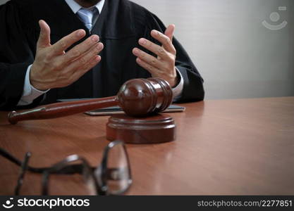 justice and law concept.Male judge in a courtroom with the gavel,working with smart phone,digital tablet computer docking keyboard,eyeglasses,on wood table