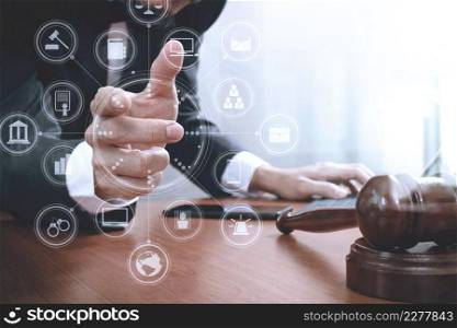 justice and law concept.Male lawyer in office with the gavel,working with smart phone,digital tablet computer docking keyboard,brass scale,on wood table,virtual interface graphic icons diagram