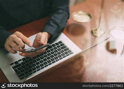 justice and law concept.Male lawyer in office with the gavel,working with smart phone,digital tablet computer docking keyboard,brass scale,on wood table,filter effect