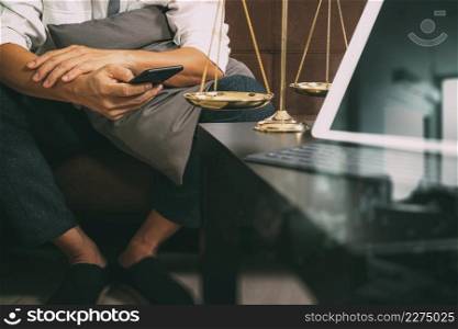 Justice and Law context.Male lawyer hand sitting on sofa and working with smart phone,digital tablet computer docking keyboard with gavel and document on living table at home,filter effect