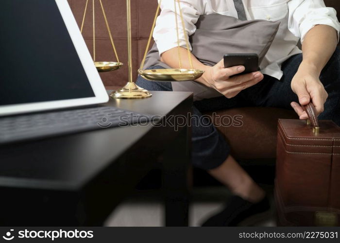 Justice and Law context.Male lawyer hand sitting on sofa and working with smart phone,digital tablet computer docking keyboard with gavel and document on living table at home