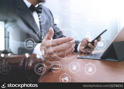 Justice and Law context.Male lawyer hand working with smart phone,digital tablet computer docking keyboard with gavel and document on wood table,virtual interface graphic icons diagram