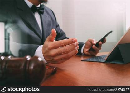 Justice and Law context.Male lawyer hand working with smart phone,digital tablet computer docking keyboard with gavel and document on wood table,filter effect