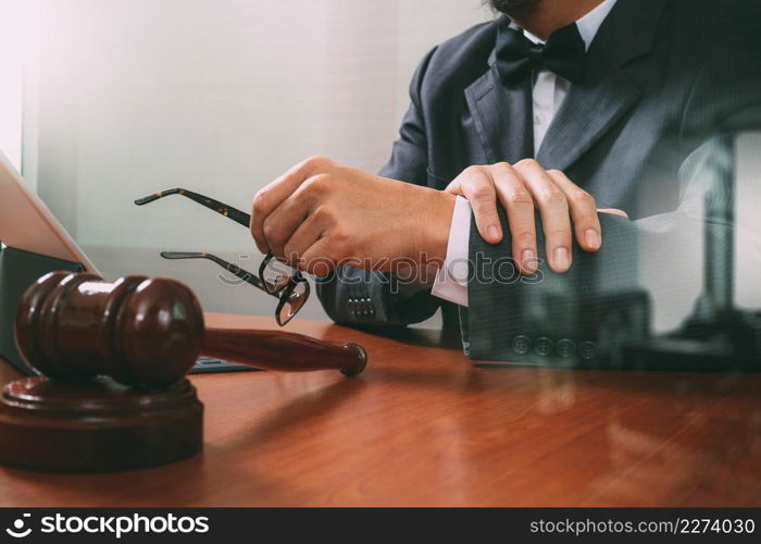 Justice and Law context.Male lawyer hand working with smart phone,digital tablet computer docking keyboard with gavel and document on wood table,filter effect