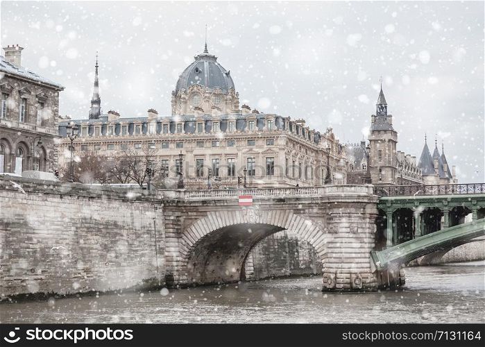 Justice Palace and Conciergerie in Paris at gloomy winter snowy day. Pastel trendy toning. Beautiful inspiring moody faded scenery