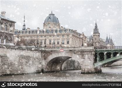 Justice Palace and Conciergerie in Paris at gloomy winter snowy day. Pastel trendy toning. Beautiful inspiring moody faded scenery
