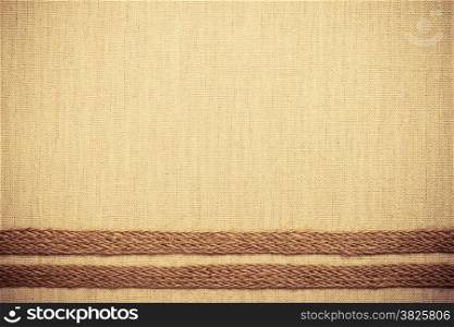 Jute bagging ribbon on bright fabric textile material, natural linen background