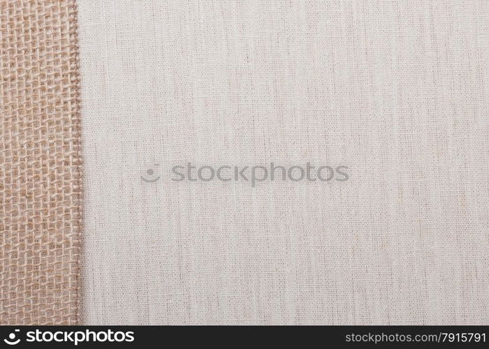 Jute bagging ribbon on bright fabric textile material, natural linen background