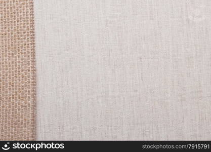 Jute bagging ribbon on bright fabric textile material, natural linen background