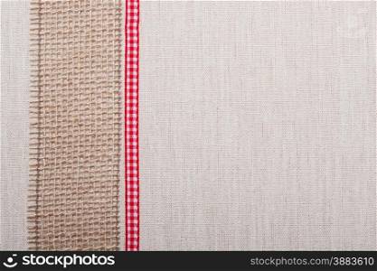 Jute mesh and red ribbon on bright fabric textile material, natural linen background