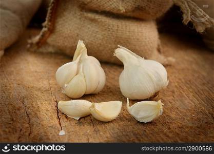 jute sack with ripe garlic on wooden board
