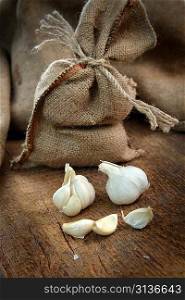 jute sack with ripe garlic on wooden board