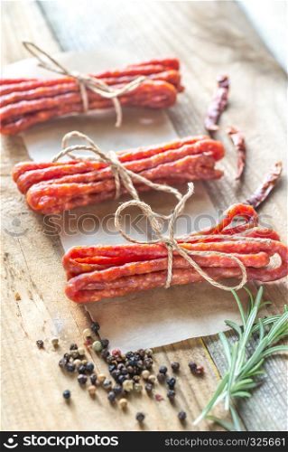 Kabanosy sausages with spices on the wooden background