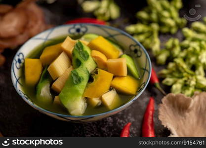 Kaeng Liang in a bowl with spices on a black cement floor.