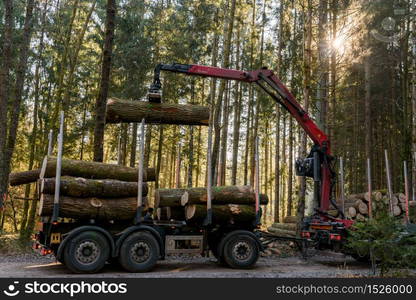 Kaiserwald, Austria - 21.01.2020: Crane in forest loading logs in the truck. Timber harvesting and transportation in forest. Transport of forest logging industry and forestry industry.. Crane in forest loading logs in the truck. Timber harvesting and transportation in forest.