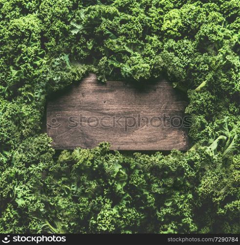 Kale leaves background frame with wooden sign. Healthy detox vegetables . Clean eating and dieting concept. Top view with copy space. Kale recipes and benefits