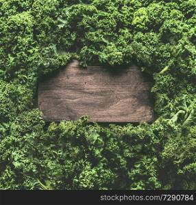 Kale leaves background frame with wooden sign. Healthy detox vegetables . Clean eating and dieting concept. Top view with copy space. Kale recipes and benefits