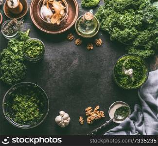 Kale recipes food background with fresh kale leaves and ingredients for pesto on dark kitchen table, top view, frame
