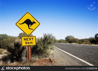 Kangaroo crossing sign by road in rural Australia.