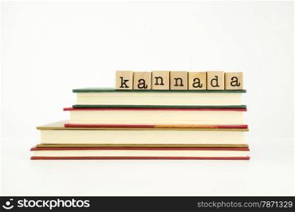 kannada word on wood stamps stack on books, foreign language and translation concept