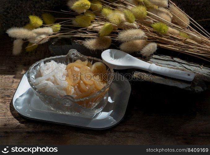 Kanom pla krim khai tao or Sweet rice noodles with coconut cream in glass bowl served with white spoon. Traditional thai dessert, Copy space, Selective focus.