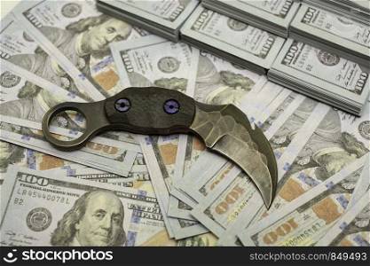 karambit knife on stack bundles of 100 US dollars banknotes bloody