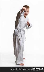 Karate boy hits with his right hand, white background