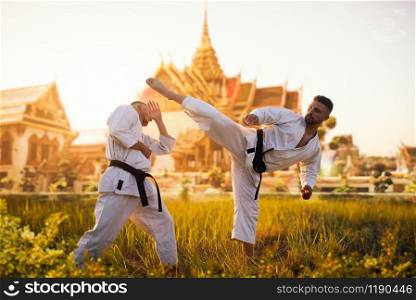 Karate fighters on training fight against ancient temple on sunset. Martial art workout outdoor. Photo manipulation with background. Karate fighters, fight against ancient temple