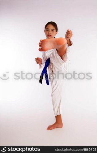 karate girl in white kimono and blue belt kicks. kick little girl