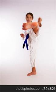 karate girl in white kimono and blue belt kicks. kick little girl