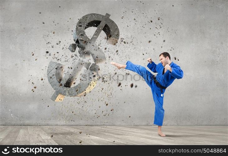Karate man attack dollar. Young determined karate man breaking with leg concrete dollar sign